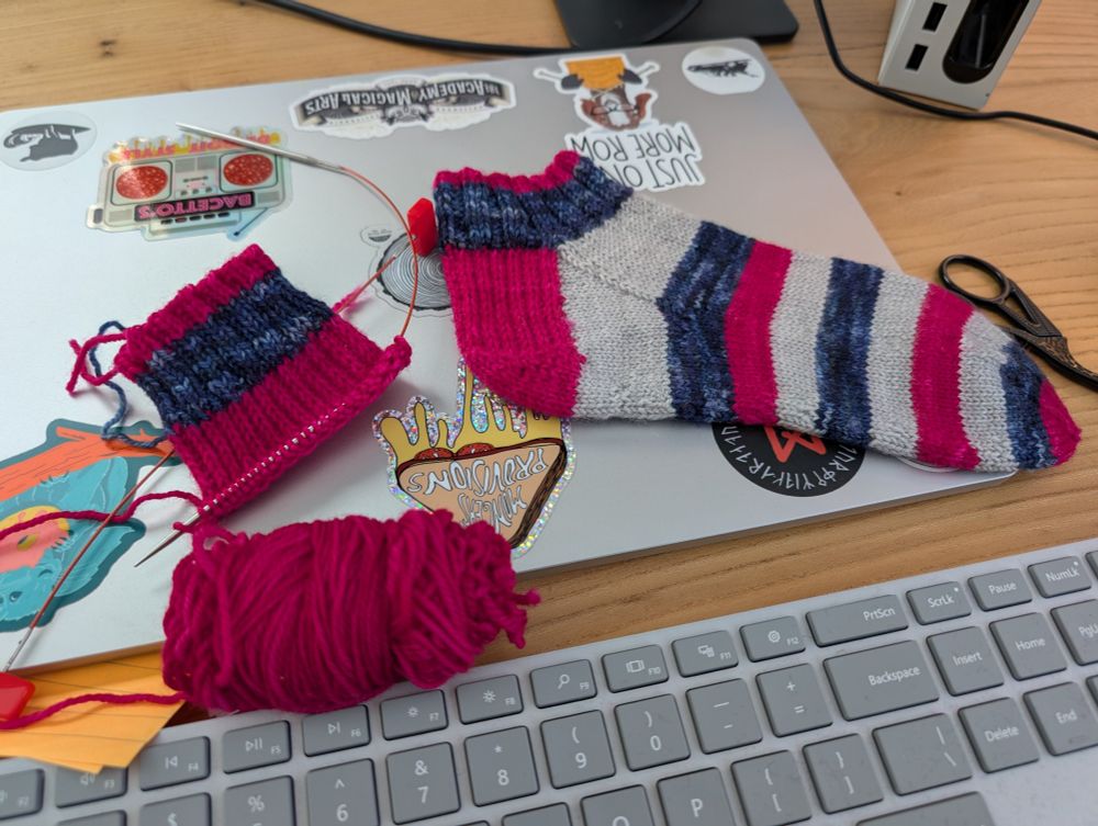 Pink blue & grey striped shortie socks. One complete, one in progress with heel partly done.
