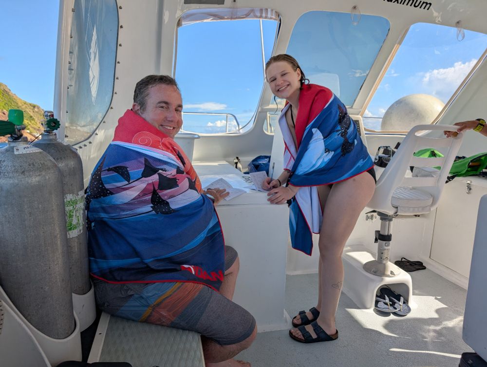 Joshua and Iris on a boat wrapped in towels filling out dive logs, looked very pleased with themselves.