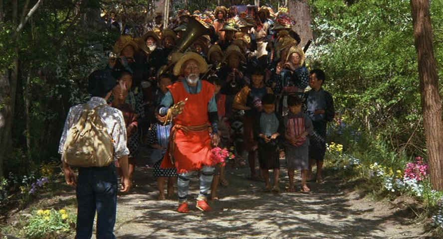 the last sequence in kurosawas dreams' last episode: in the village of the watermills, the funeral parade is coming by the avatar/the dreamer, which is probably a young kurosawa himself. the old man, who was telling a story before, is going on front of the parade and leading it, with some sort of metal percussion instrument. he picked some flowers before, that he holds in his hand. with this scene, the movie ends and fades out over a long time, with wonderful chantings.
