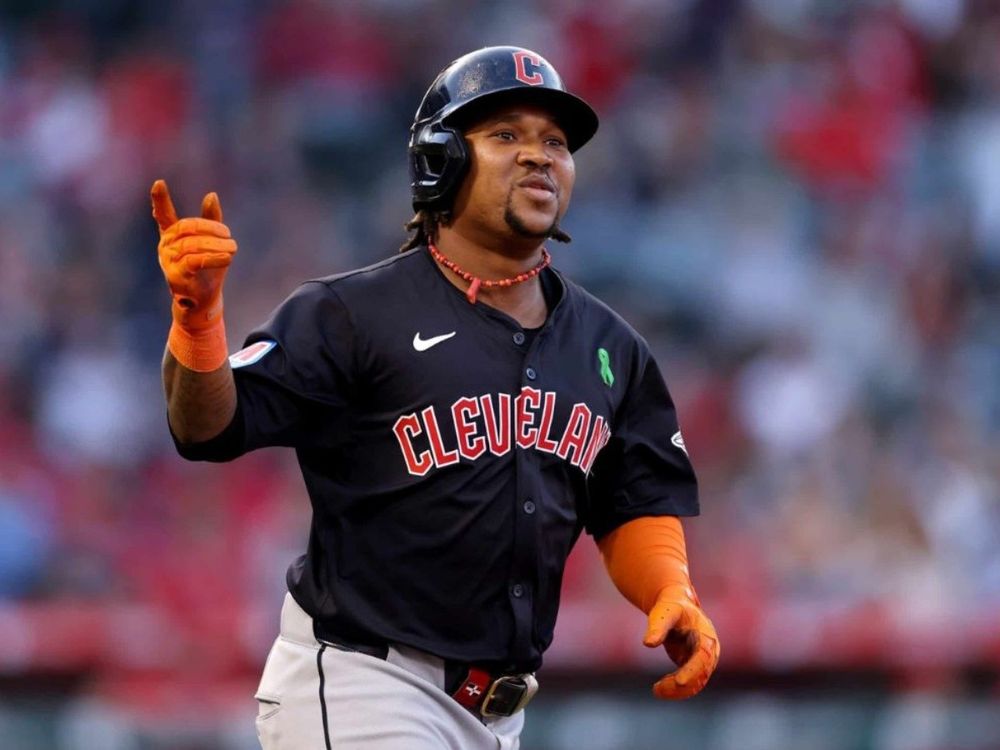 Jose Ramirez points to a fan while wearing a blue Cleveland jersey. 