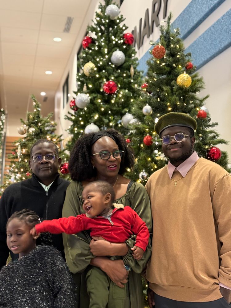 A picture of a family in front of a Christmas tree. 