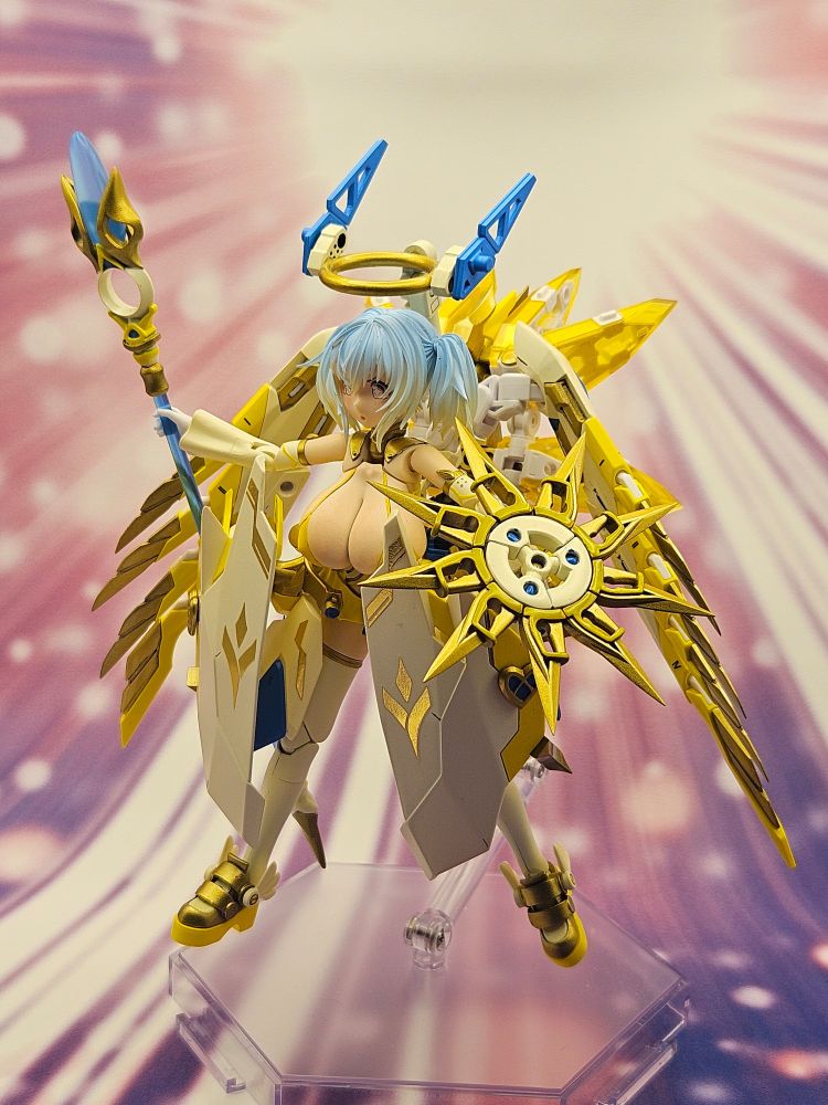 A photograph of a Megami Device custom model kit. Her name is Ginger and she's modeled after a mechanical archangel theme. She has a shortstack figure, and light blue hair with short twintails. Her outfit and mech armor have a palette of white, radiant yellow, and gold, emulating the bright sun. Her gear includes a pair of robe panels covering her front, a pair of side skirts with thrusters, a pair of mechanical wings, a back attachment, a staff tipped with a teardrop gem, and a mechanical halo floating above her head. She poses defiantly with her staff raised.