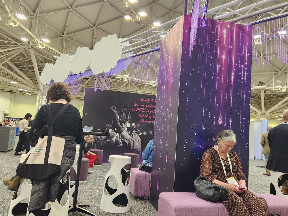 Librarians relaxation in purple and white loungers and tables against a printed purple background. Purple lights and beaded curtains hang above. A large background featuring Prince reads "Dearly beloved we are gathered this day to get through this thing called librarianship."