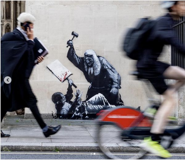 New Banksy Work Seen as Comment on U.K. Crackdown on Palestine Action
The mural that appeared outside the Royal Courts of Justice in London on Monday depicted a judge attacking a demonstrator with a gavel.