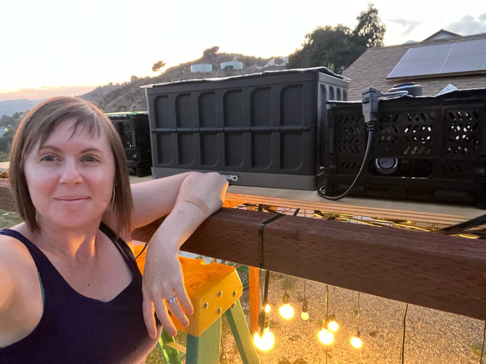 Selfie of me on a ladder showing the crates I just discussed in place with cables coming out of them. Lights are on below me in the structure. 