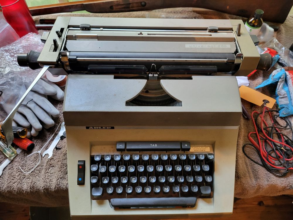 Adler Universal 200 manual typewriter on a work bench.  Two tone color tan and brown.
