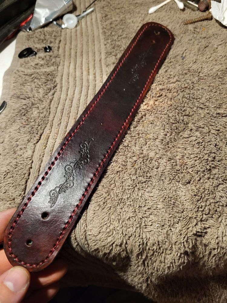 Dark brown leather bracelet with red border stitching and floral patterns.