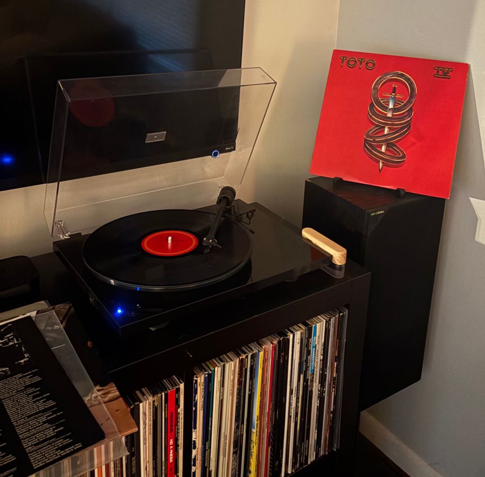 The album cover. Artwork of a sword interleaving 4 rings set against a bright red background. The band name and album cover are written in the upper corners.