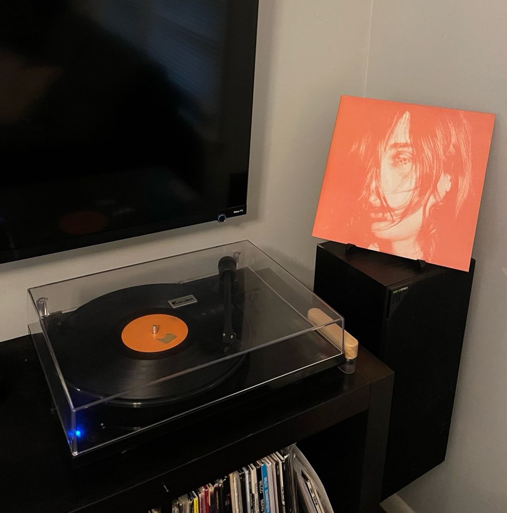 The album cover: an orange and white photograph of the lead singer (Bradford Cox) with long hair over his face covering his nose and one eye. Inside of his other eye is a skull.