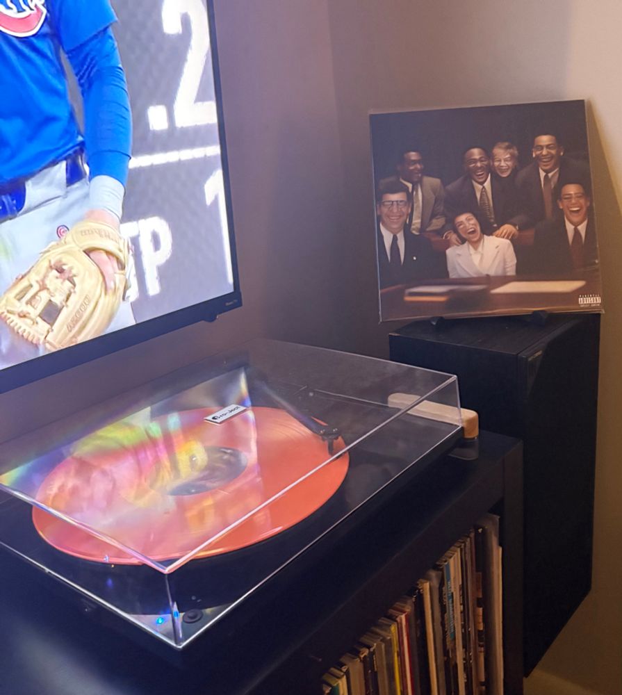 the album cover; it's some ai generated art of a group of business professionals seated at a desk. their faces are all grotesquely distorted in that early-gen AI way