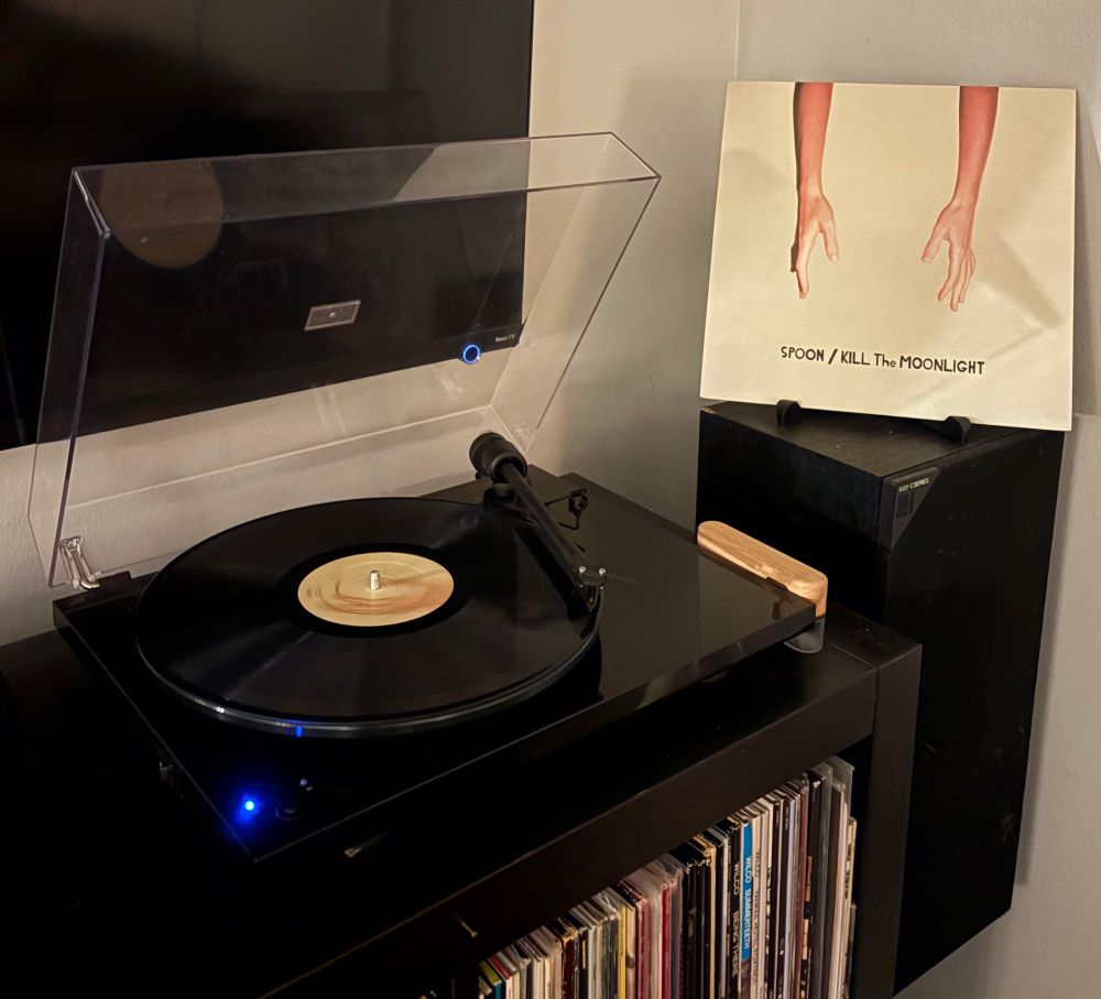 The album cover. Two arms outstretched towards the text of the band / album in a hand written looking font against cream background