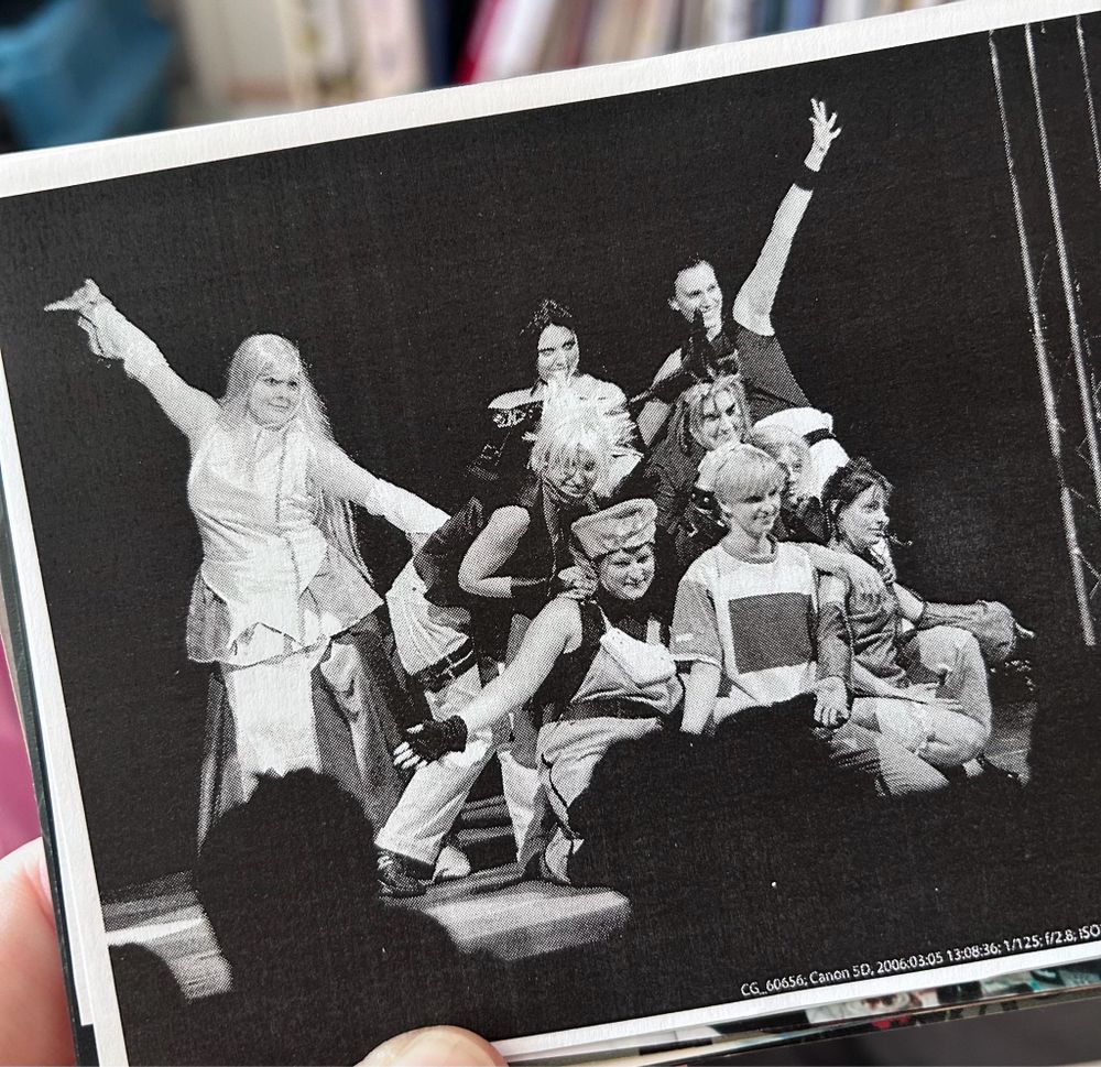 Ein schwarz-weiß Bild einer Gruppe von jungen Frauen, die in verschiedenen Kostümen auf einer Bühne posieren.