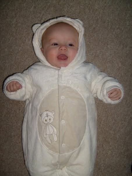 My daughter as a small baby, in a white babysuit smiling