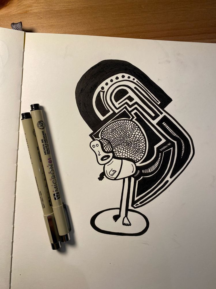 Drawing in ink in a sketchbook of a strange guy. Intricate patterns of black and white space lay above his back. Micron pens lie to the left of the drawing. 