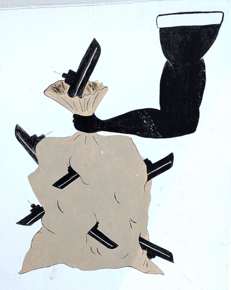 HMSC Sackville's gunplate art.  Shown is a large arm holding a brown sack, with multiple U-Boats trying and failing to escape from the sack.  