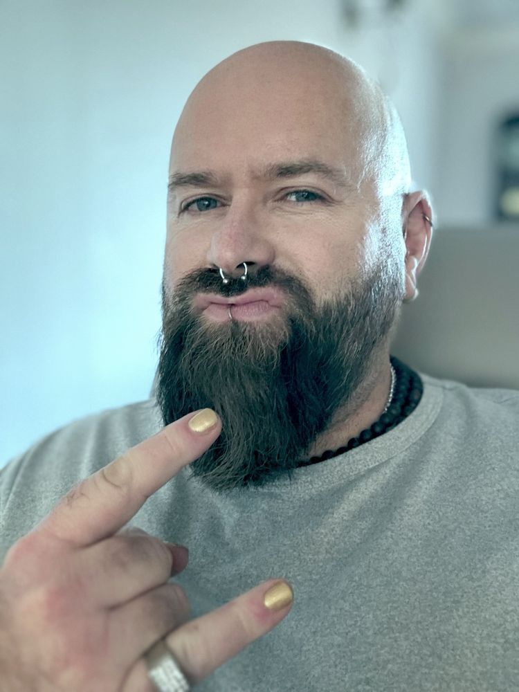 Image shows Rob doing duck face and the horn sign with his hand. He’s wearing a grey tee. He’s a smug asshole and it shows. 