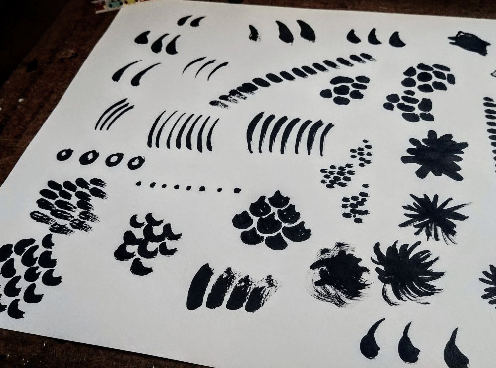 Assorted black ink shapes and brush-strokes on white paper.