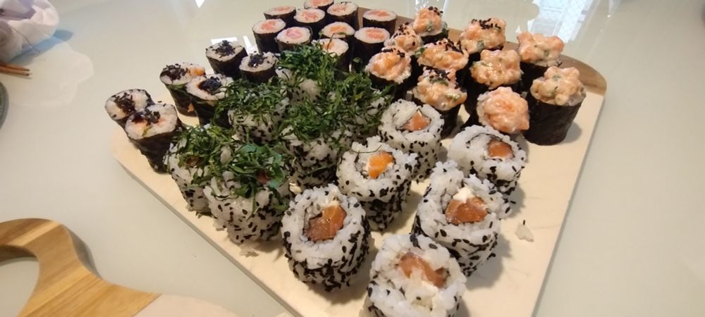 sushis diversos postos em uma base de pedra clara sobre uma mesa branca