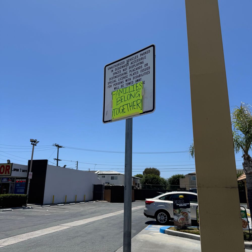 Street sign with a taped sign over it that reads “Families belong together!” And they do!
