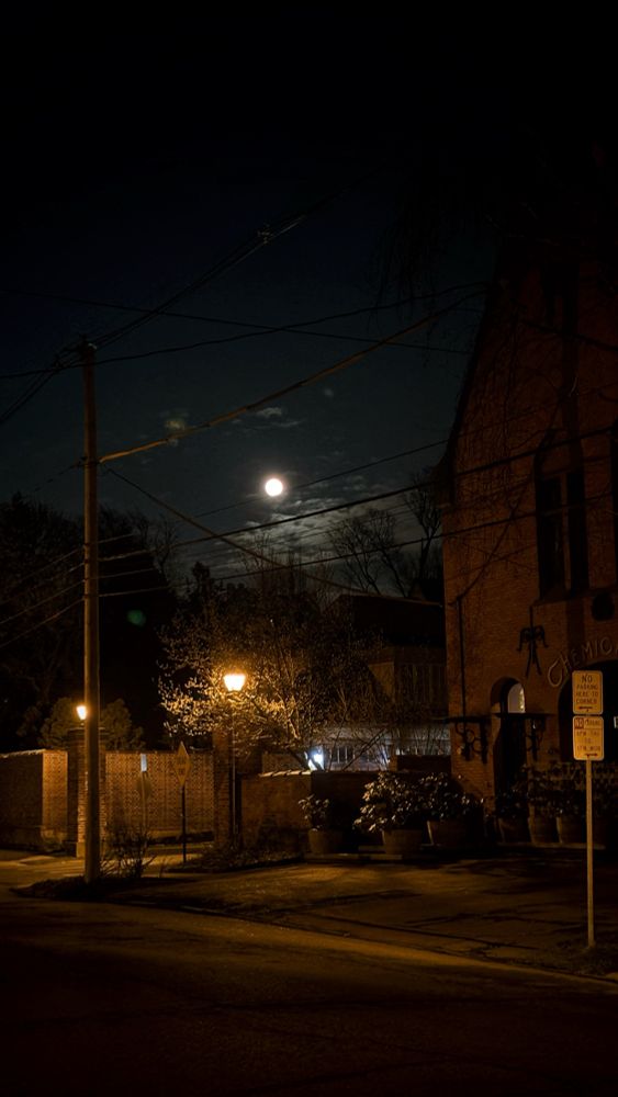 full moon in the night sky above a street with lamps