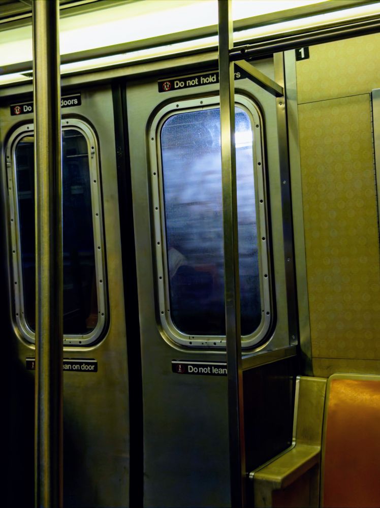 Subway doors with harsh, blue light shining through into a warmly-lit interior.