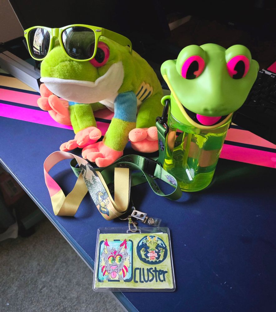 The same id in front of a plush frog wearing green sunglasses and a rainforest cafe chacha the frog water bottle 