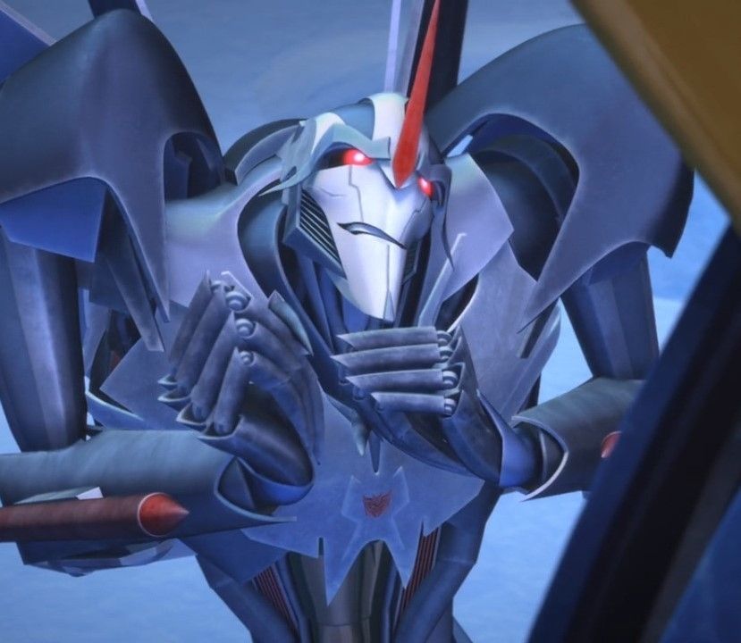 Starscream as he appears in Transformers Prime (sleek, stylised transformer in a cool grey colourscheme with red accents and pointy bits everywhere including a big pointy head fin) with his fists bunched looking tense