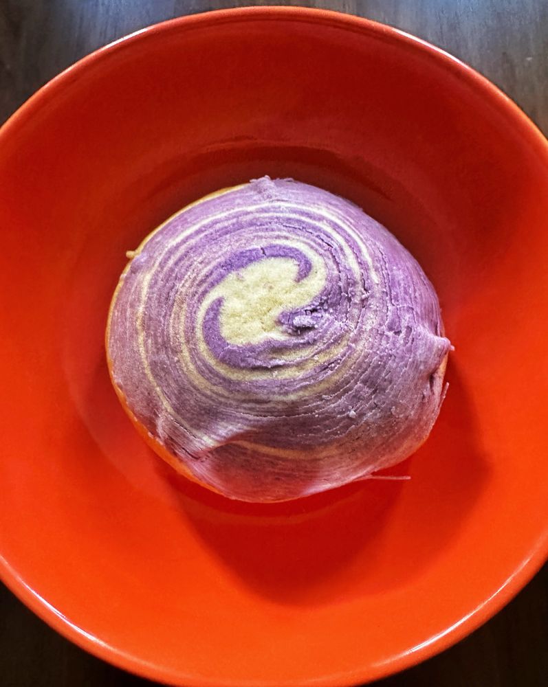 Taro pastry with purple swirls in an orange bowl.