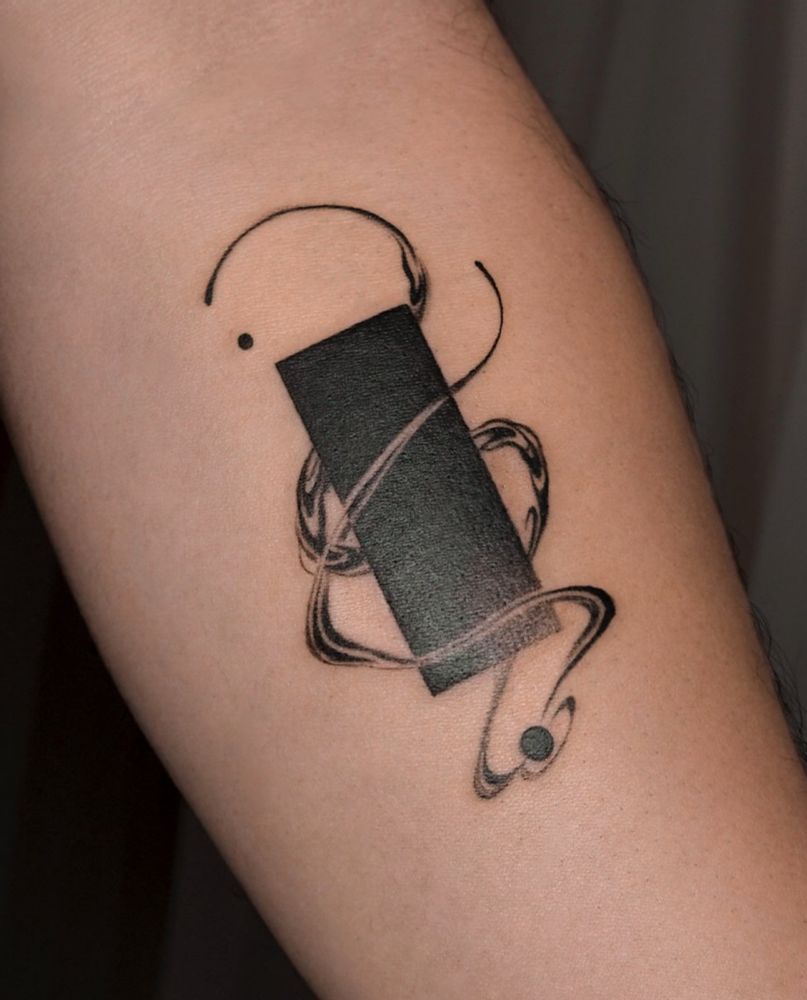 A black in tattoo of an obelisk/rectangle with ethereal & cosmic smoke lines revolving around its form. The tattoo is on a forearm with its palm side facing the camera and is slightly angled 