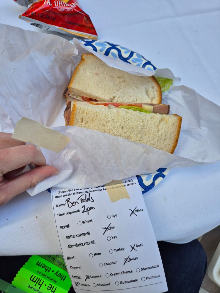 My sandwich, white bread, beef, swiss cheese, lettuce, tomato, with an order slip beneath listing these stipulations