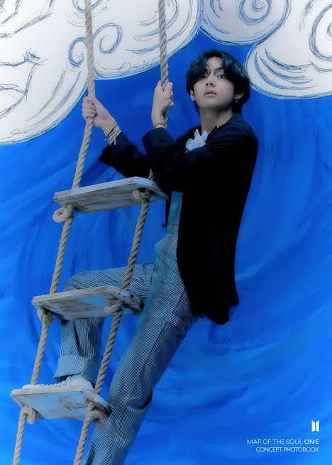 Kim Taehyung on a rope ladder in a navy jacket and jeans, in front of a whimsical blue sky with clouds background 