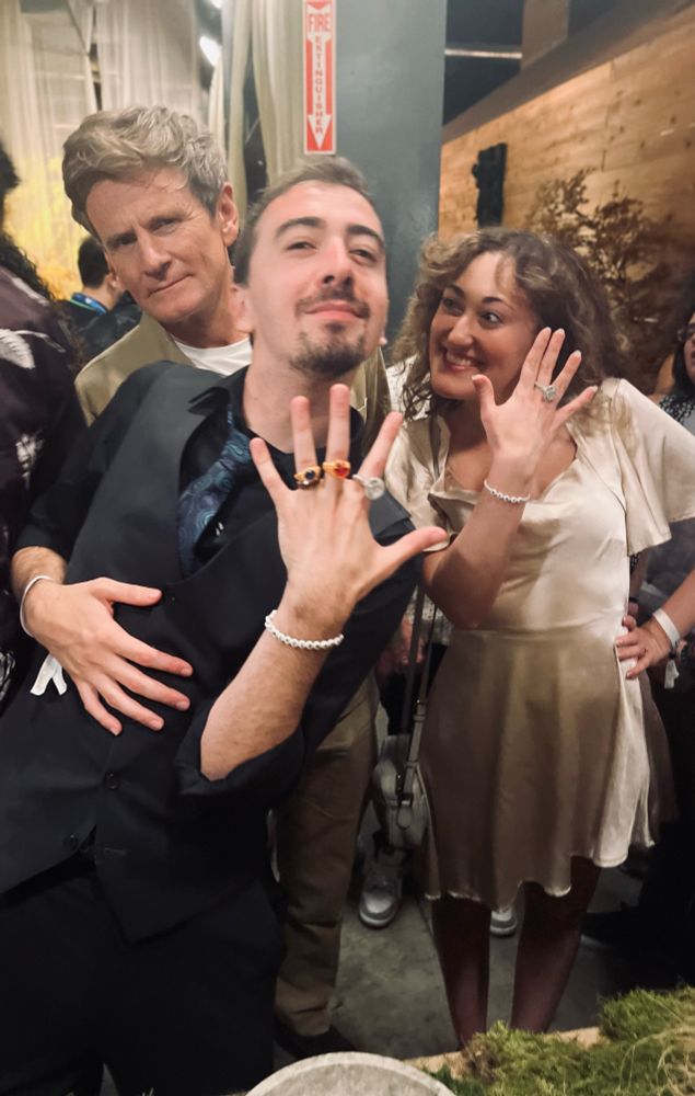 Charles Edwards, the actor who plays Celebrimbor in The Rings of Power looks somewhat confused as two influencers, DonMarshall72 and Silmaremily hold up their hands to show the 3D printed elven rings of power they just received. 