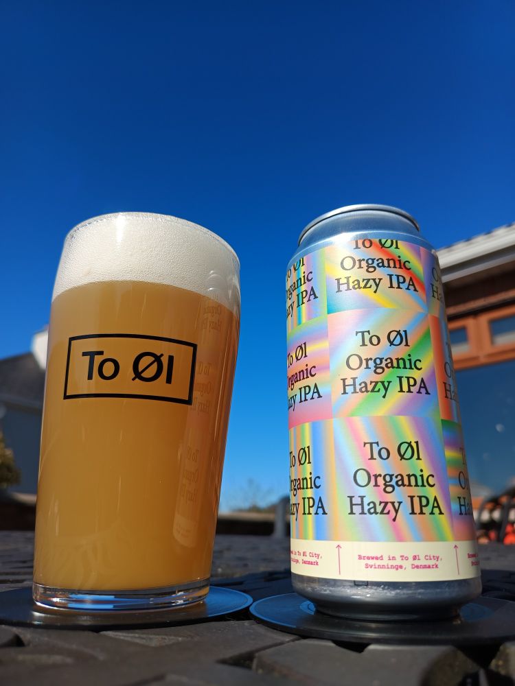 A glass and can of to øl hazy IPA with blue sky in the background 