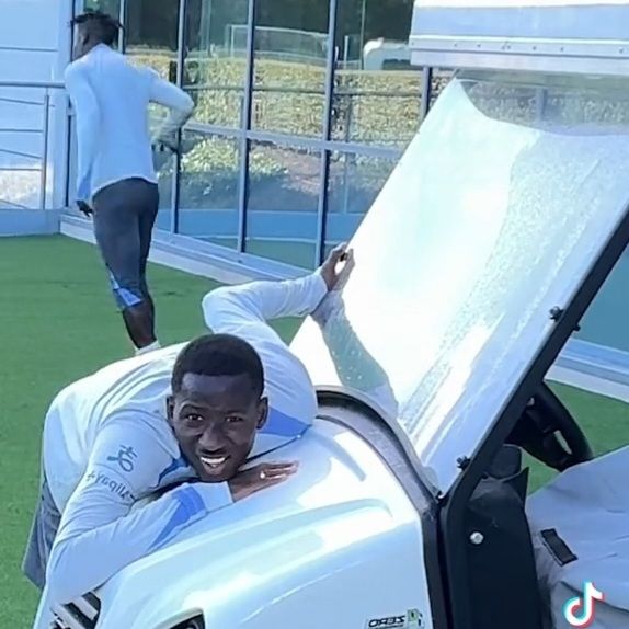 Pape Matar Sarr leaning over the front of a golf buggy.