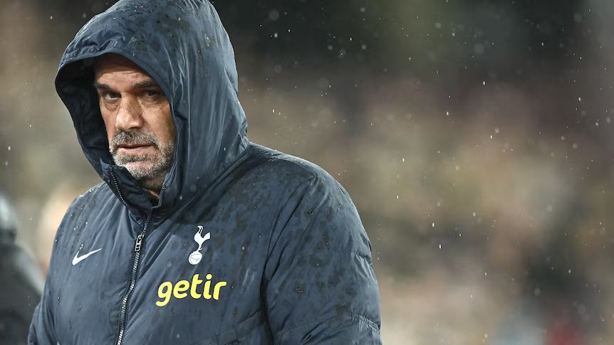 Ange Postecoglou wearing a Tottenham jacket, with his hood up in the rain.