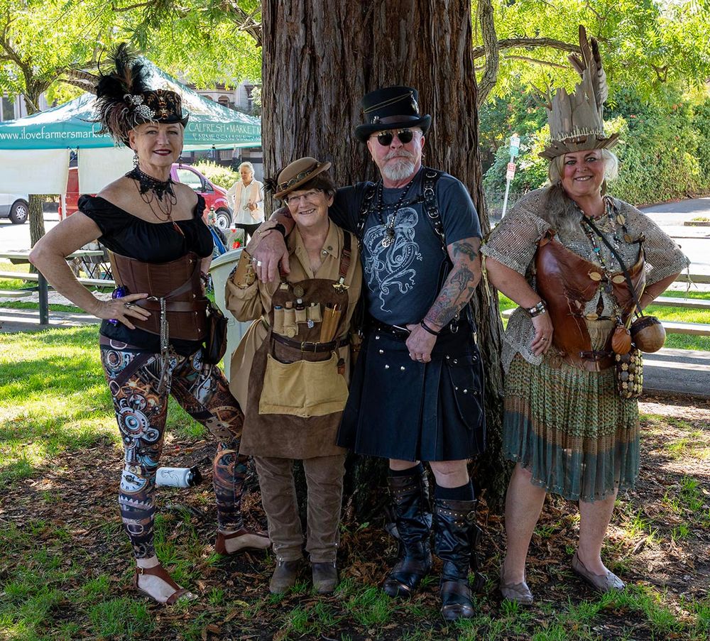 Costumed attendees at SteampTopia, posing in front of a tree.