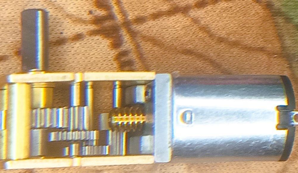 A small electric Motor with an open brass gearbox showing many cogs
