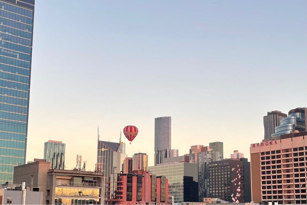 A white and red striped hot air balloon floats very low among the buildings