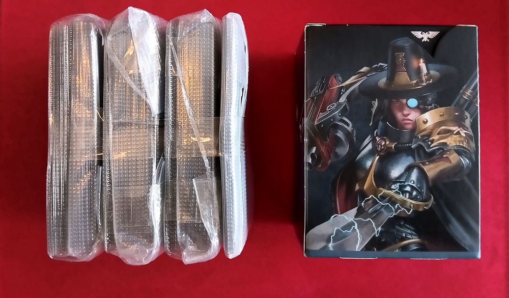 A Magic the Gathering Warhammer 40K Imperium Commander deck in vacuum sealed bags beside the deck box on red velvet leather background.