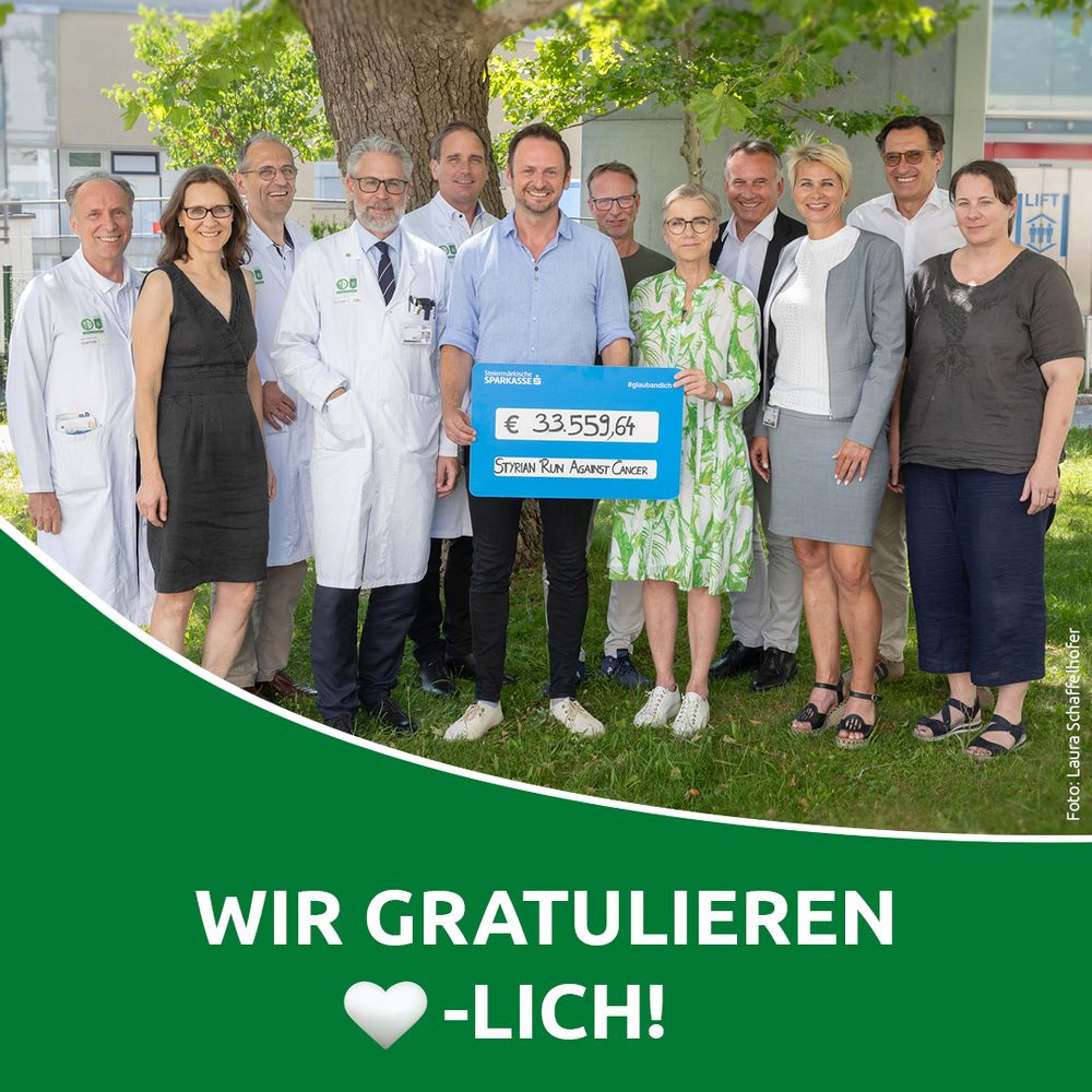 eine Gruppe von Menschen steht zusammen und hält einen Scheck