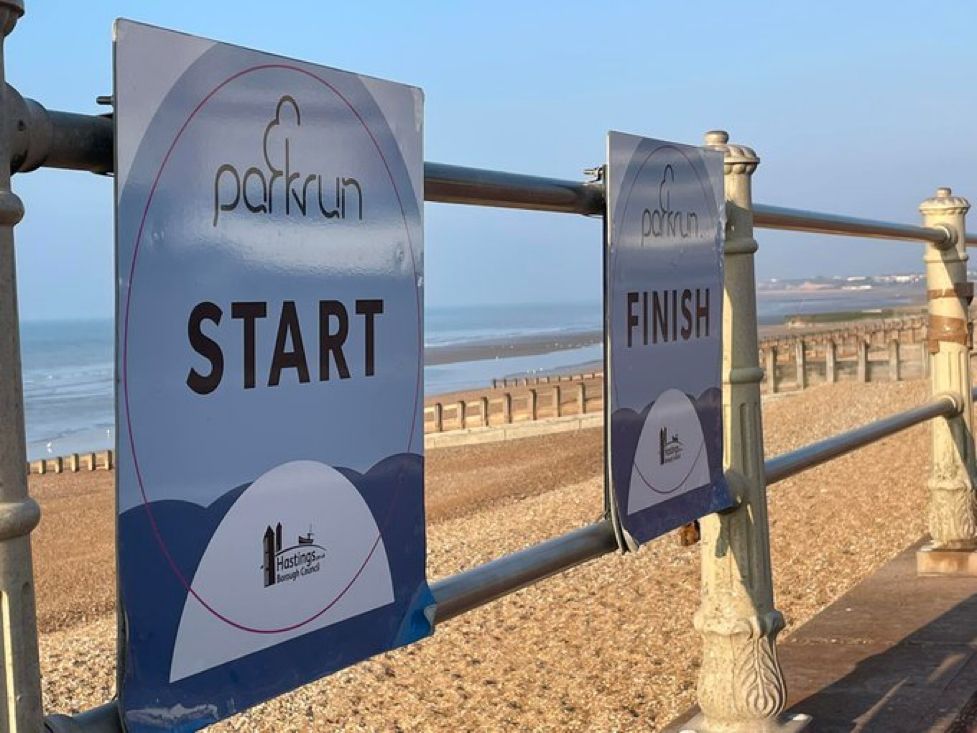 2 parkrun signs next to each other, “Start” and “Stop”, next to a beach 