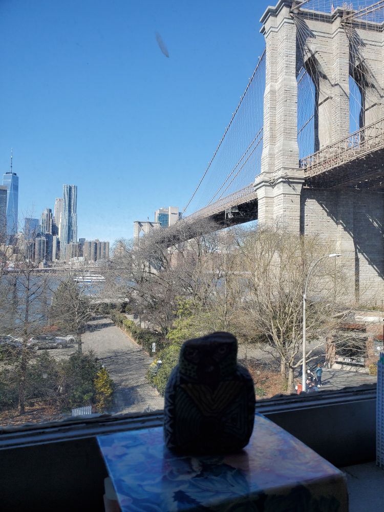 Buddo replica looking out of the window at Brooklyn Bridge, New York, USA. 