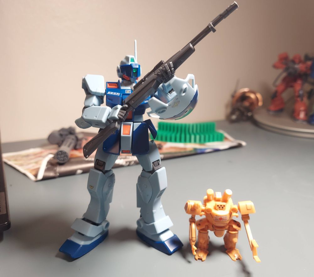 A GM Sniper II stands next to a very small orange robot whose name I do not know.