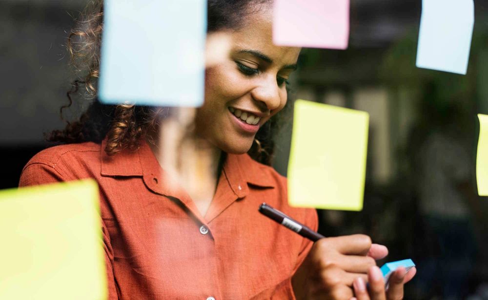 Photo d'une femme organisant ses notes sur des post-its. Photo : © Getty Images / istockphoto.com / Rawpixel