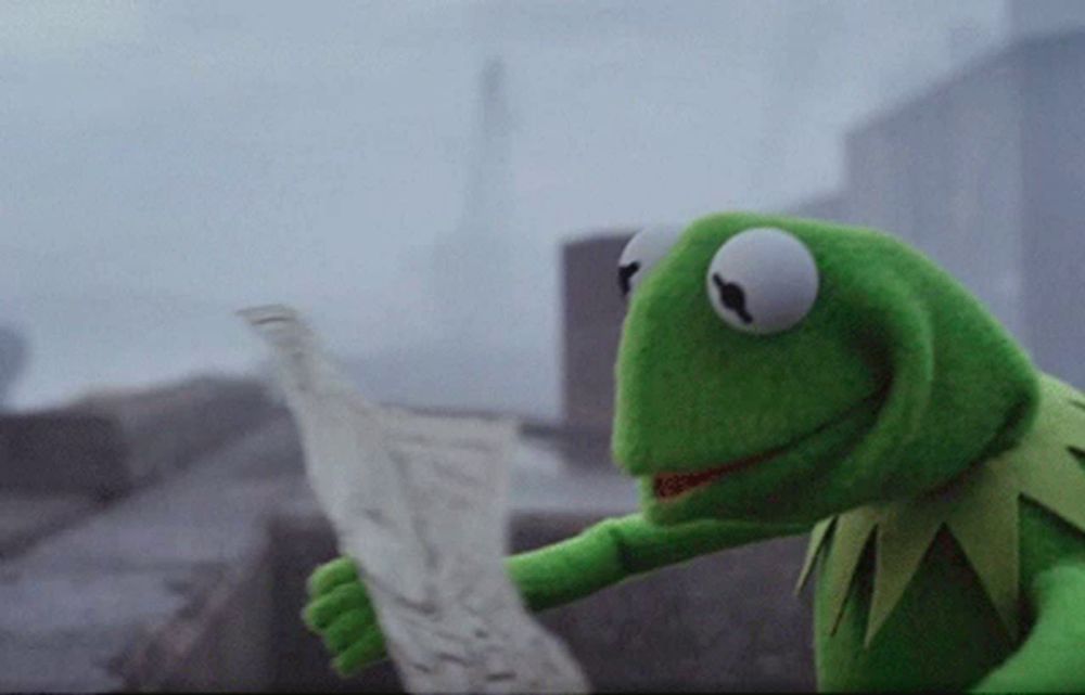 a kermit the frog is holding a piece of paper in his hand