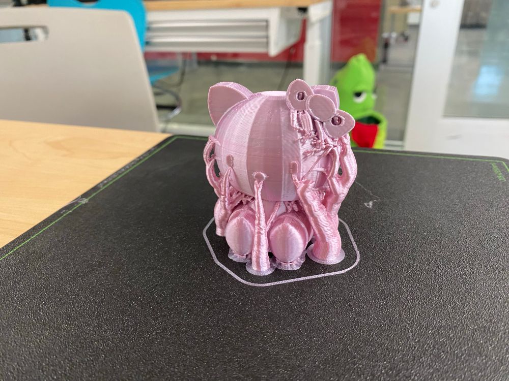 3D printed Hello Kitty figurine on a black mat. The supports are still attached to the figure.