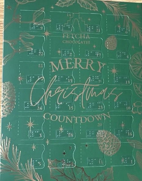 Advent calendar with a green background and gold accents, featuring the text "Merry Christmas Countdown" in the centre. The calendar has 24 numbered doors arranged in a grid pattern, each with a Braille label below the printed number. The top of the calendar reads "Fetch a Chocolates." The design is decorated with festive elements such as pine cones, stars, and leaves.