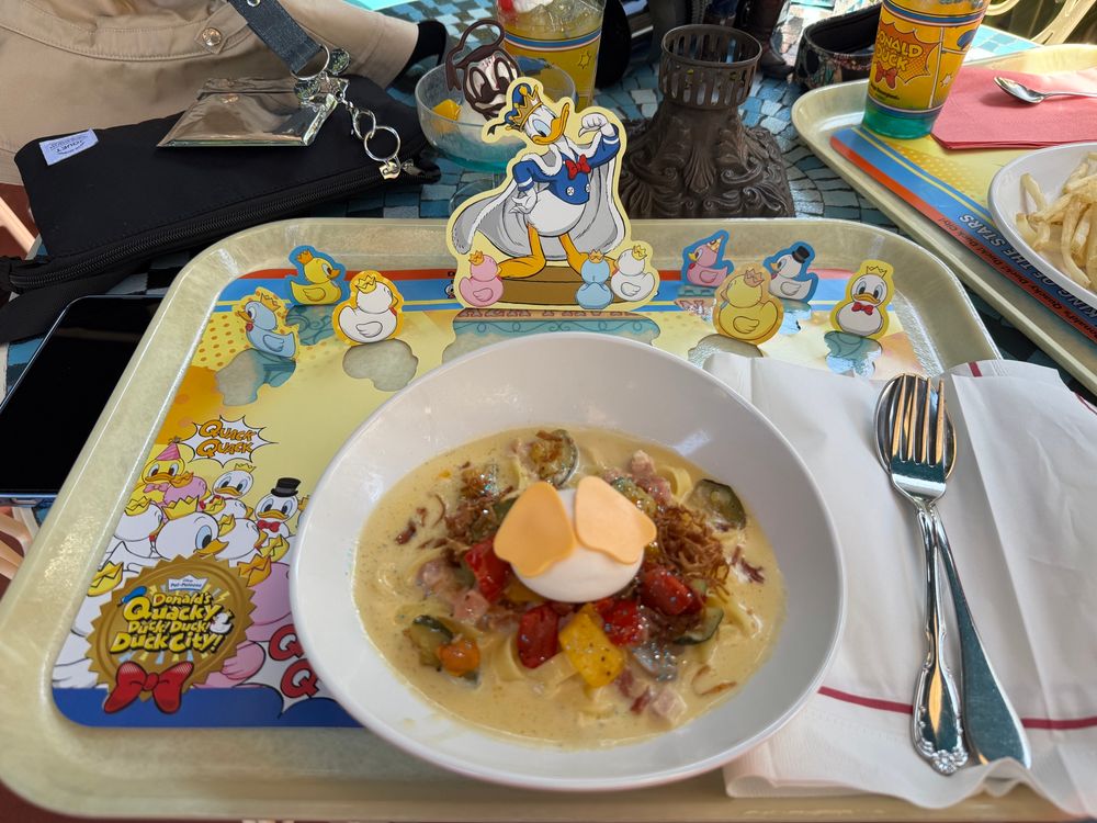 プラザパビリオンレストランにて、期間限定クリームパスタ。ドナルドのお尻をイメージした温玉がかわいい。ドヤ顔ドナルドのランチョンマットも最高。