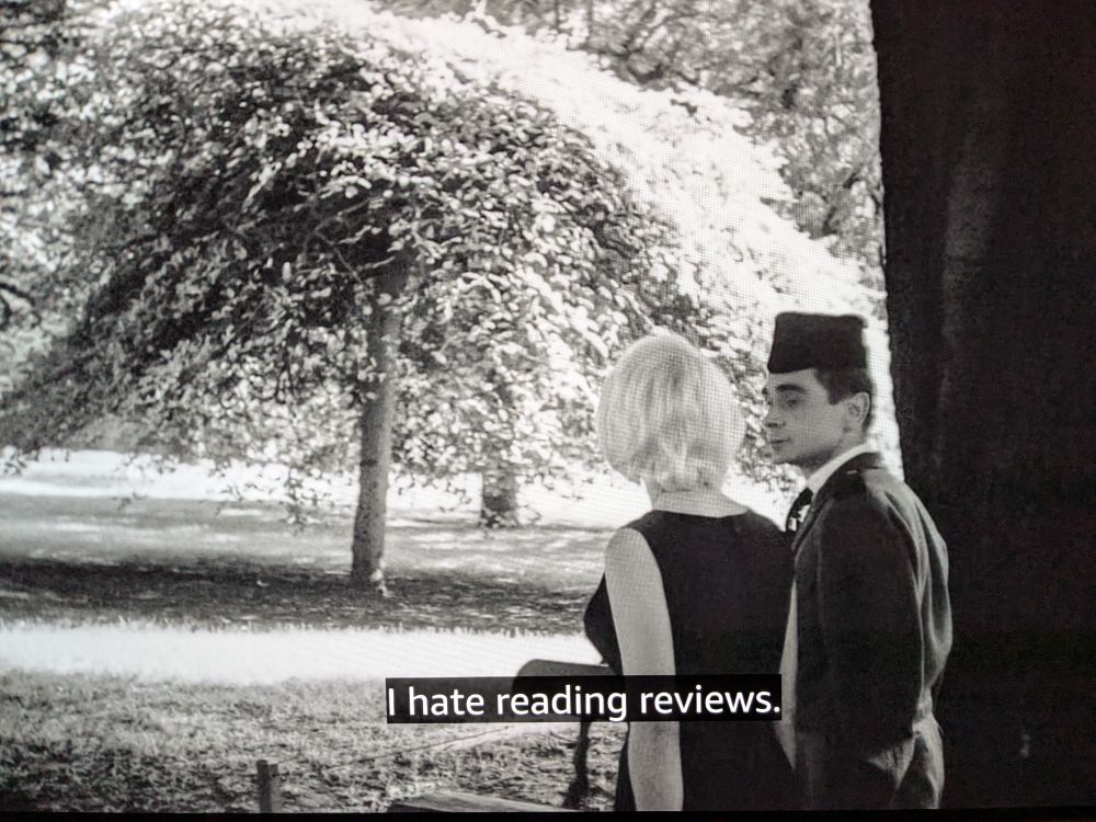 Photo of TV screen showing 'Cleo from 5 to 7'. A woman and a man are walking in a park. Subtitle: "I hate reading reviews."
