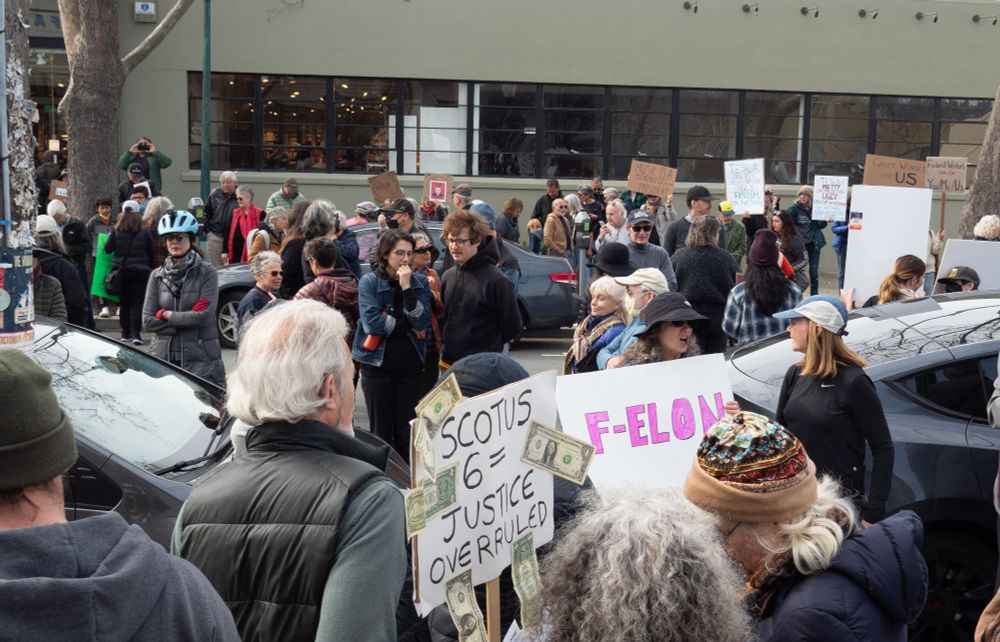 Photo from Tesla protest in Berkeley, CA on Saturday, Feb 15, 2025. Crowd shot. One sign reads: "SCOTUS 6 = JUDGE OVERRULED." Another hand-drawn sign reads, "F-ELON." Photo by Shana DeClercq